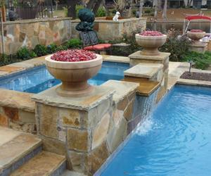 Remodeled Swimming Pool in Plano with stone steps and decking as well as a waterfall from the spa to the pool